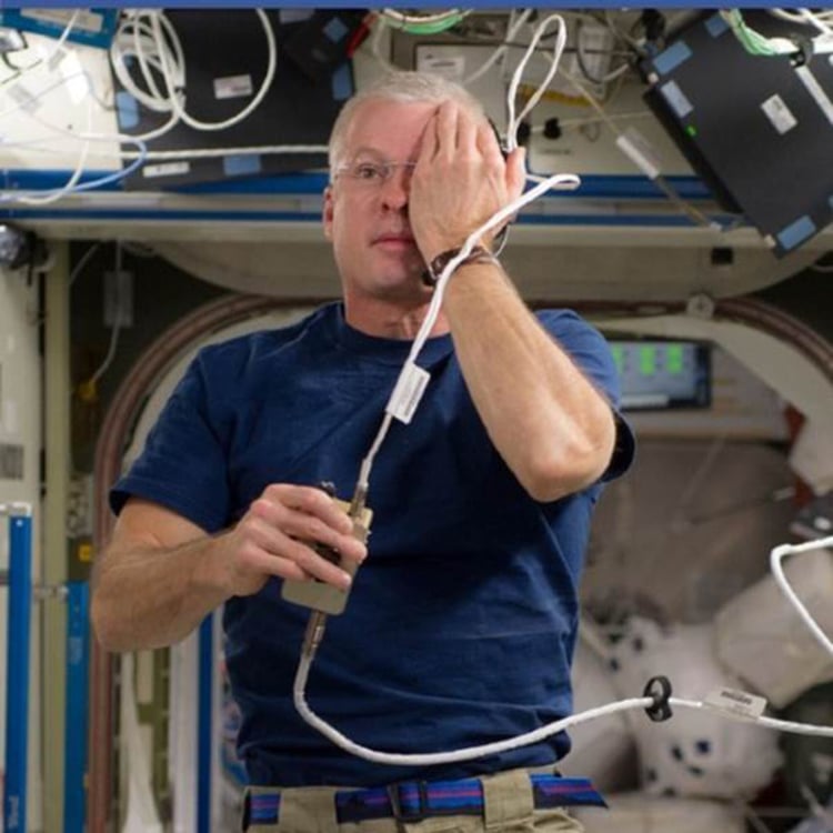 Astronaut using acuitypro's vision testing system aboard the international space station, covering one eye during an eye exam.