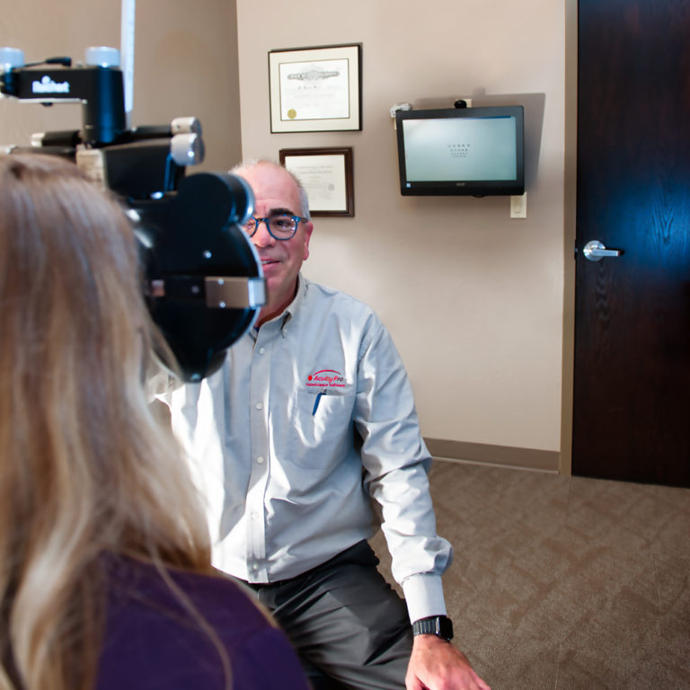 Optometrist conducting a visual acuity test using acuity pro software and digital eye chart.